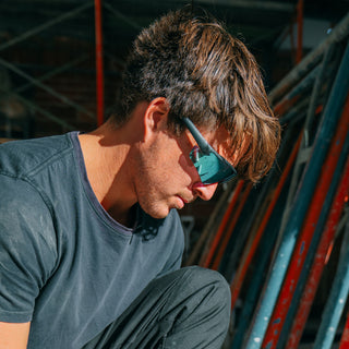 Matte black Phantoms safety glasses with blue lenses, worn on a person's face, full-face view