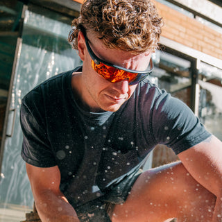 Matte black Phantoms safety glasses with red lenses, worn on a person's face, frontal view